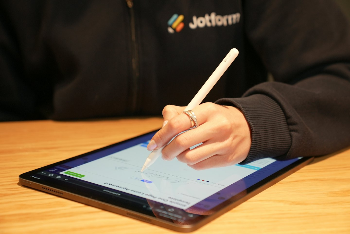 Person signs digital document on tablet with stylus.